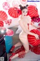 A naked woman sitting on a bed with red lanterns.