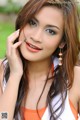 A woman in an orange and white top posing for a picture.