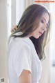 A woman in a white shirt leaning against a window.