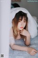 A woman laying on a bed under a white sheet.