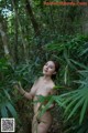 A naked woman standing in the middle of a forest.