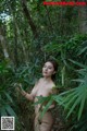 A naked woman standing in the middle of a forest.