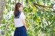 A woman in a school uniform standing next to a tree.