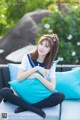 A woman sitting on a blue couch with a blue pillow.