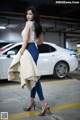 A woman standing in a parking garage next to a white car.