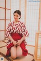 A woman in a red and white kimono sitting on the floor.