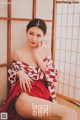 A woman in a red and white kimono sitting on the floor.