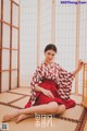 A woman in a red and white kimono sitting on the floor.