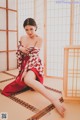 A woman in a red and white kimono sitting on the floor.