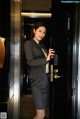 A woman in a business suit standing in front of a door.