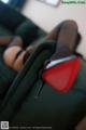 A woman in black stockings and red high heels sitting on a green couch.