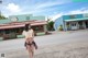 A woman walking down the street in front of a building.