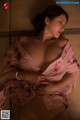 A woman in a pink robe laying on a bed.