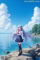 A girl with long purple hair standing on a rock by the water.