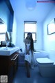 A woman in a white towel standing in a bathroom.