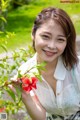 A woman holding a red flower in her hand.