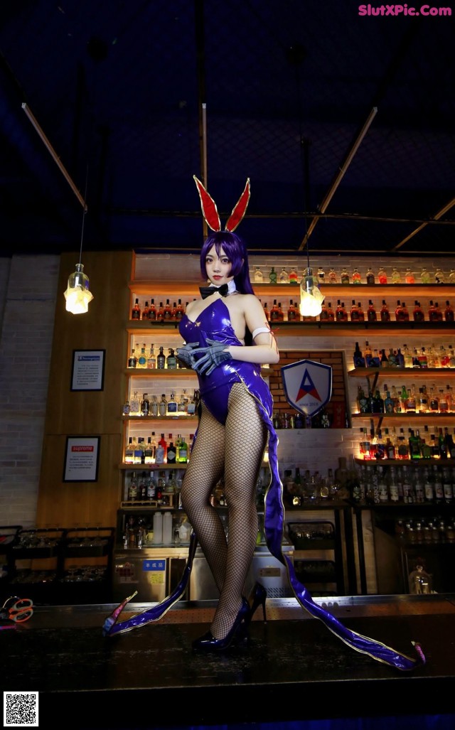 A woman in a bunny costume standing in front of a bar.