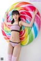 A woman in a bikini standing next to a giant lollipop.