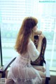 A woman sitting on a chair in front of a window.