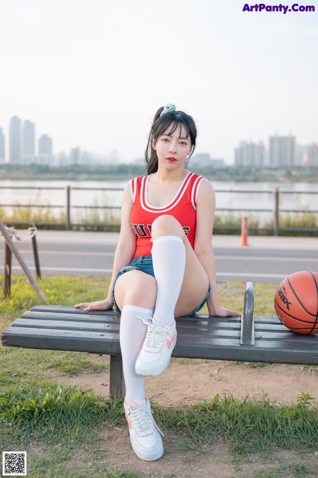 A woman sitting on a bench with a basketball.