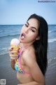 A woman in a bikini eating an ice cream cone.