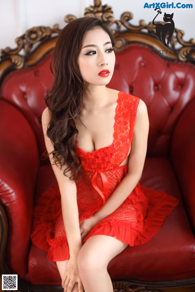 A woman in a red dress sitting on a red chair.