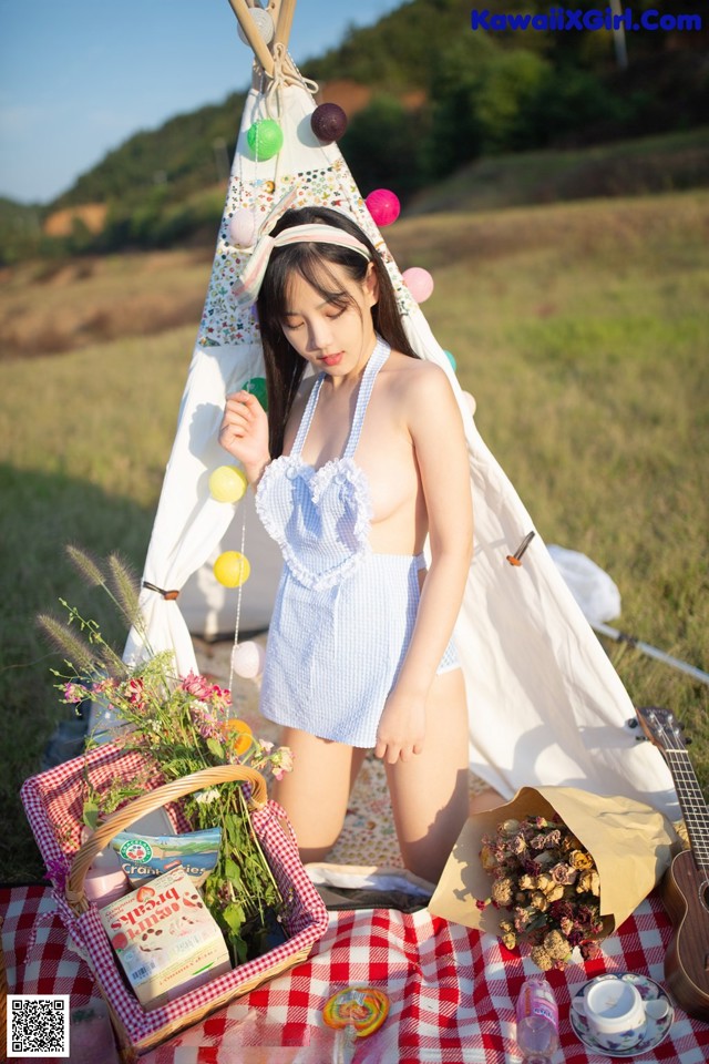 A woman in a blue and white bathing suit sitting on a picnic blanket.