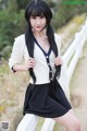 A woman with long black hair posing on a white fence.