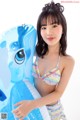 A woman in a bikini holding an inflatable blue pony.