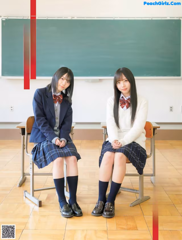 A couple of girls sitting on top of a wooden floor.
