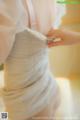 A woman is putting on a wedding dress. 