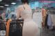 A woman in a white dress standing next to a shopping cart.