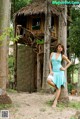 A woman in a blue dress posing in front of a tree house.