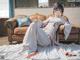 A woman in a white kimono sitting on a brown couch.