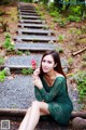 A woman in a green dress sitting on a train track.