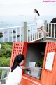 A woman in a white dress standing on a balcony next to the ocean.