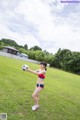 A woman in a bikini holding a soccer ball in a field.