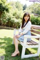 A woman sitting on a bench in a park.