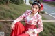 A woman in a red and white dress sitting on a fence.